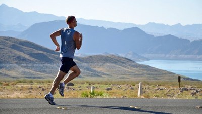 A man running on a road next to a lake
