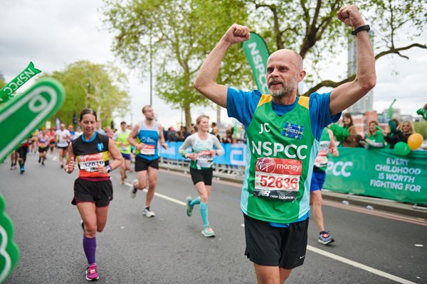 Man in NSPCC vest running and cheering