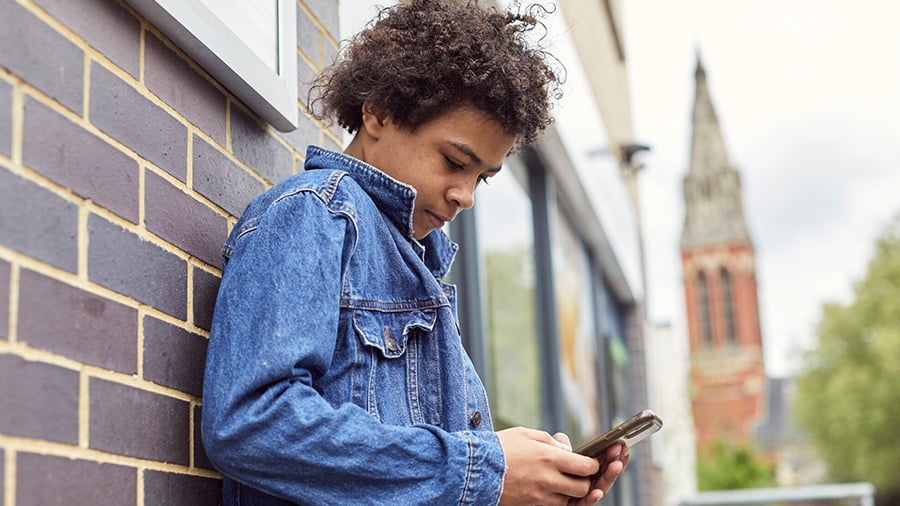 Young boy on phone sitting in bus stop