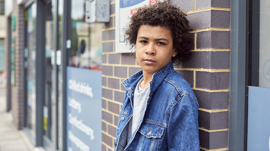 Young boy standing outside in street wearing coat