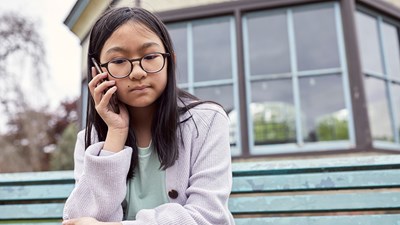 Girl sitting on a bench with a mobile phone to her ear