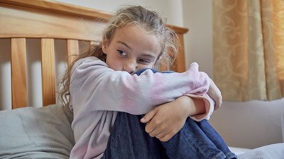 Girl sitting on bed looking sad or worried