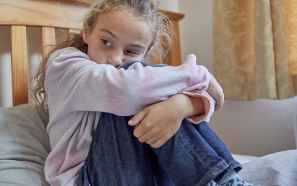 Girl sitting on bed looking sad