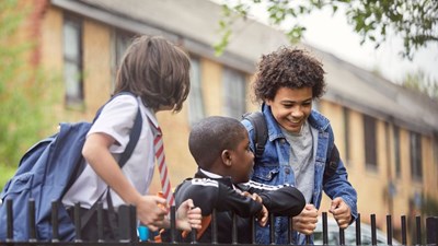 Three school children smiling by railings