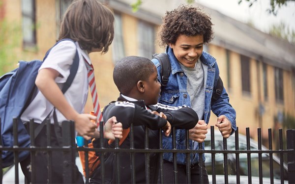 Three school children smiling by railings