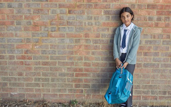 Girl in school uniform standing in front of brick wall