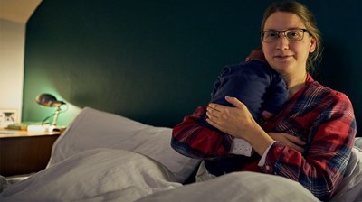 A woman lying on a bed holding her new born baby.