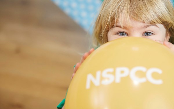 A young girl blowing up a balloon.