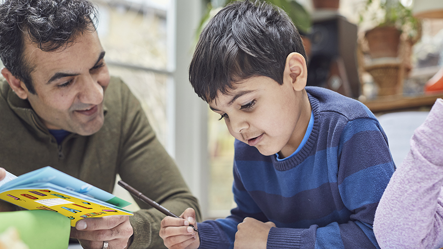 Asian man reading with young Asian boy