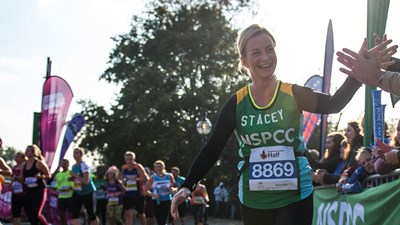 Woman in NSPCC vest running and smiling