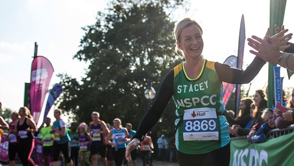 Woman in NSPCC vest running and smiling