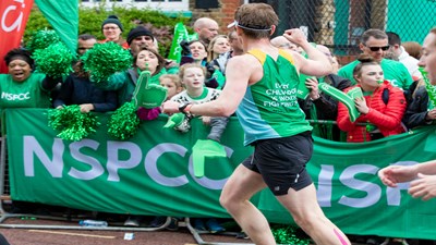 A Team NSPCC runner cheering while running past a cheer point.