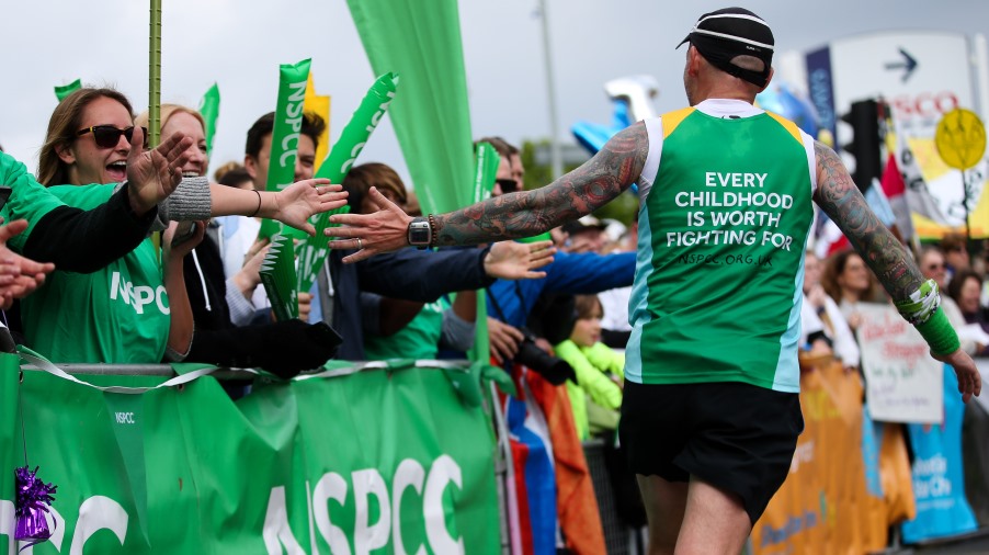 marathon runner touching hands of cheerers as he runs past