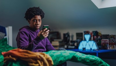 Photograph of a young person alone and using their phone.