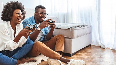 Two adults laughing and smiling while playing a video game.