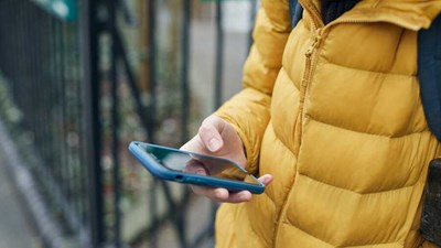 A child wearing a yellow bodywarmer is looking at their phone