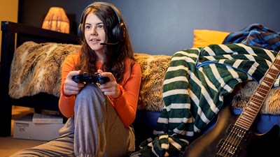 A teenager smiling while playing a video game.