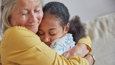 An elderly woman hugging her grandchild.