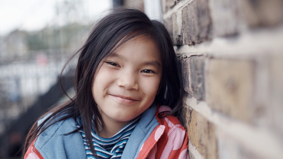 Girl leaning against a wall and smiling to camera