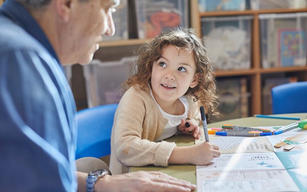 A young girl using a colouring in book.