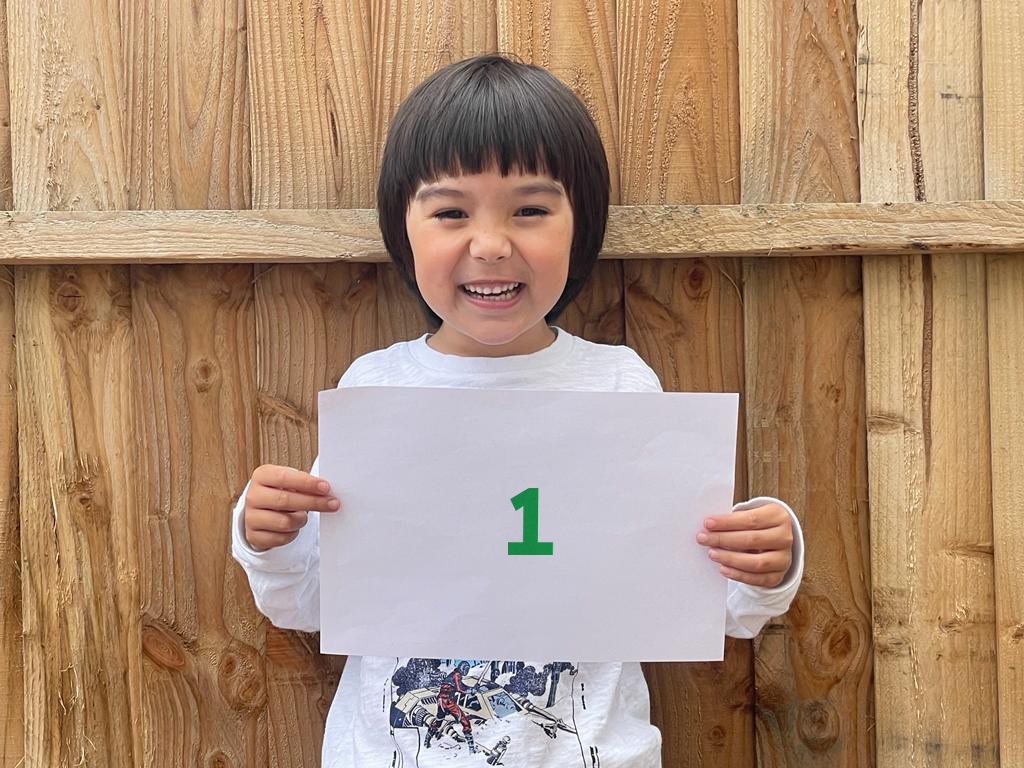 Young girl smiling and holding a sign with the number 1 on it