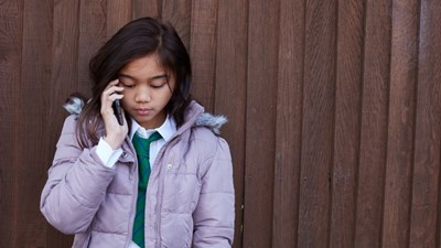 Teenage girl in the street speaking on a mobile phone