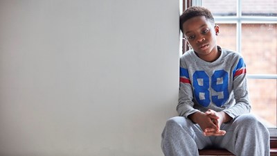 A young boy sat by a window while staring into the distance.