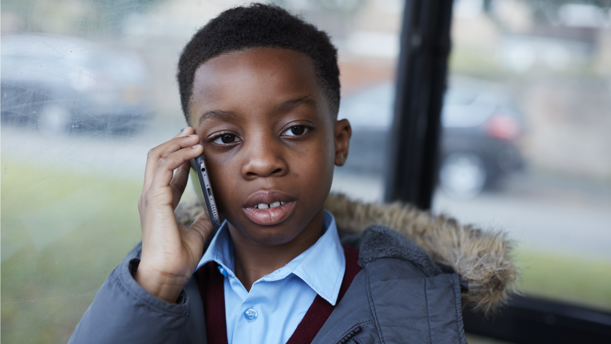Young boy on phone sitting in bus stop