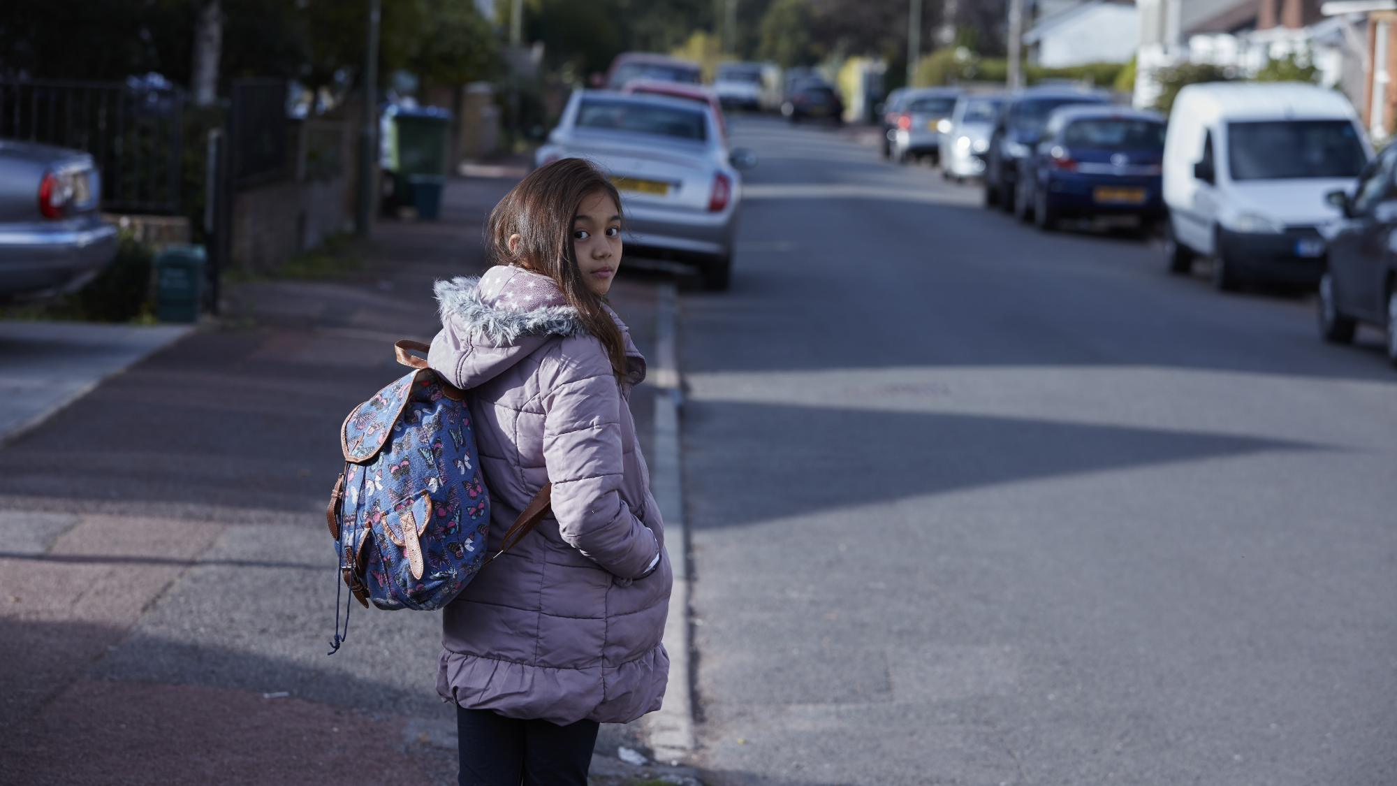 Young girl walking along road, looking over shoulder