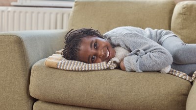 A young girl smiling while lying on a sofa.