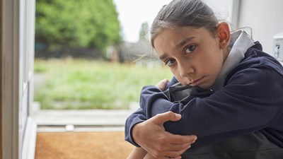 A young child sat on the floor looking sad.