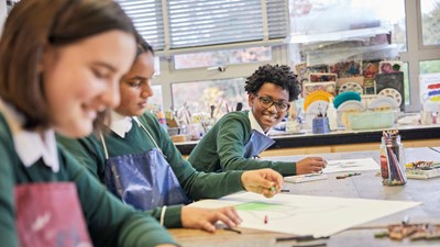 A teenage boy smiling while drawing at school.