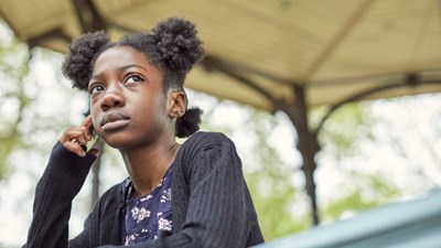 A teenage girl talking on her mobile while looking worried.