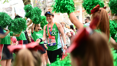 An NSPCC runner with medal surrounded by cheerleaders