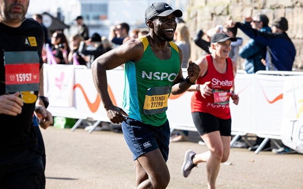 Black man smiling and running in marathon