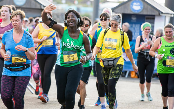 Team NSPCC runner waving to a cheering point