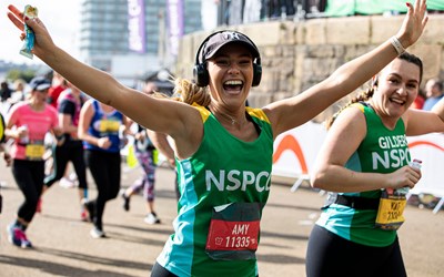 Woman in NSPCC vest running and smiling