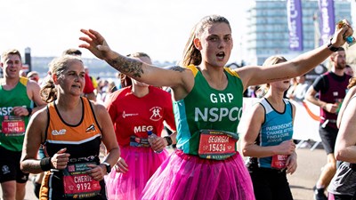 A Team NSPCC member running and smiling during the Cardiff Half Marathon.