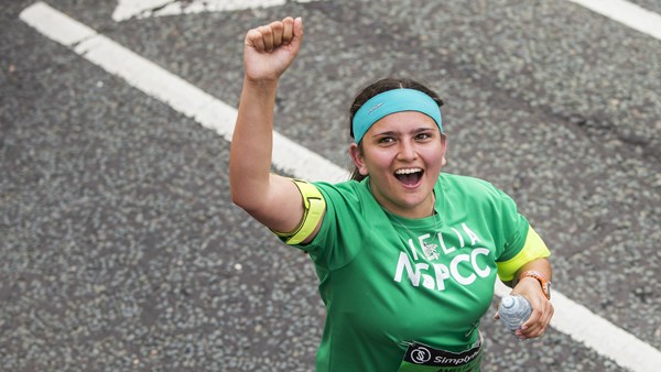 A Team NSPCC runner cheering while taking part in a race.