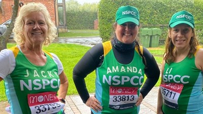 A group of women in green NSPCC running vests smiling into the camera.