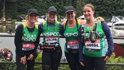 A group of women in green NSPCC running vests smiling into the camera.