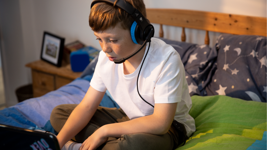 Boy playing on laptop with headset