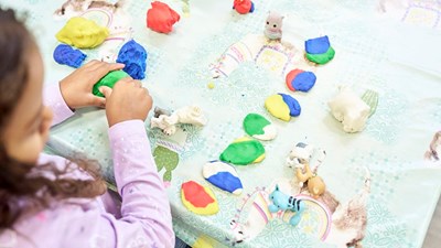 Young girl plays with colourful modelling clay.