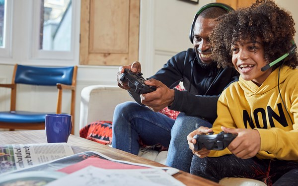 A parent/carer and their child playing a video game together in their living room.