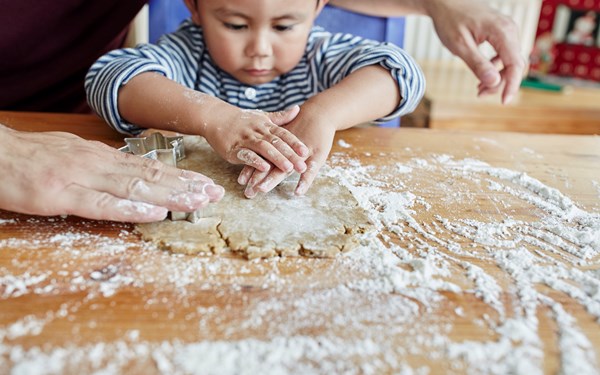 A toddler cutting out gingerbread shapes