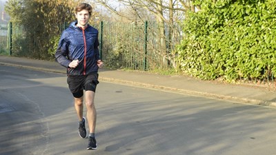 A man running on a road wearing a waterproof jacket