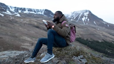 A man sits on grass holding headphones