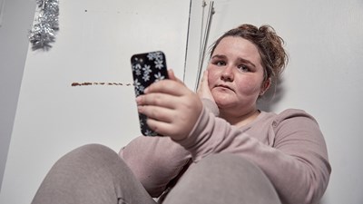Teenage girl sat on floor with mobile phone.