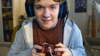 A teenage boy smiling while playing on a video game.