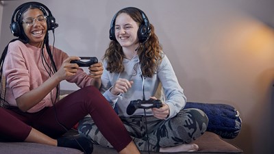 Two teenagers laughing and smiling while playing a video game.